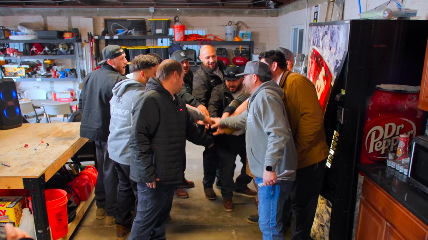 Ramco project photo — the Ramco crew piling their hands in for a huddle in the shop before the day’s calls